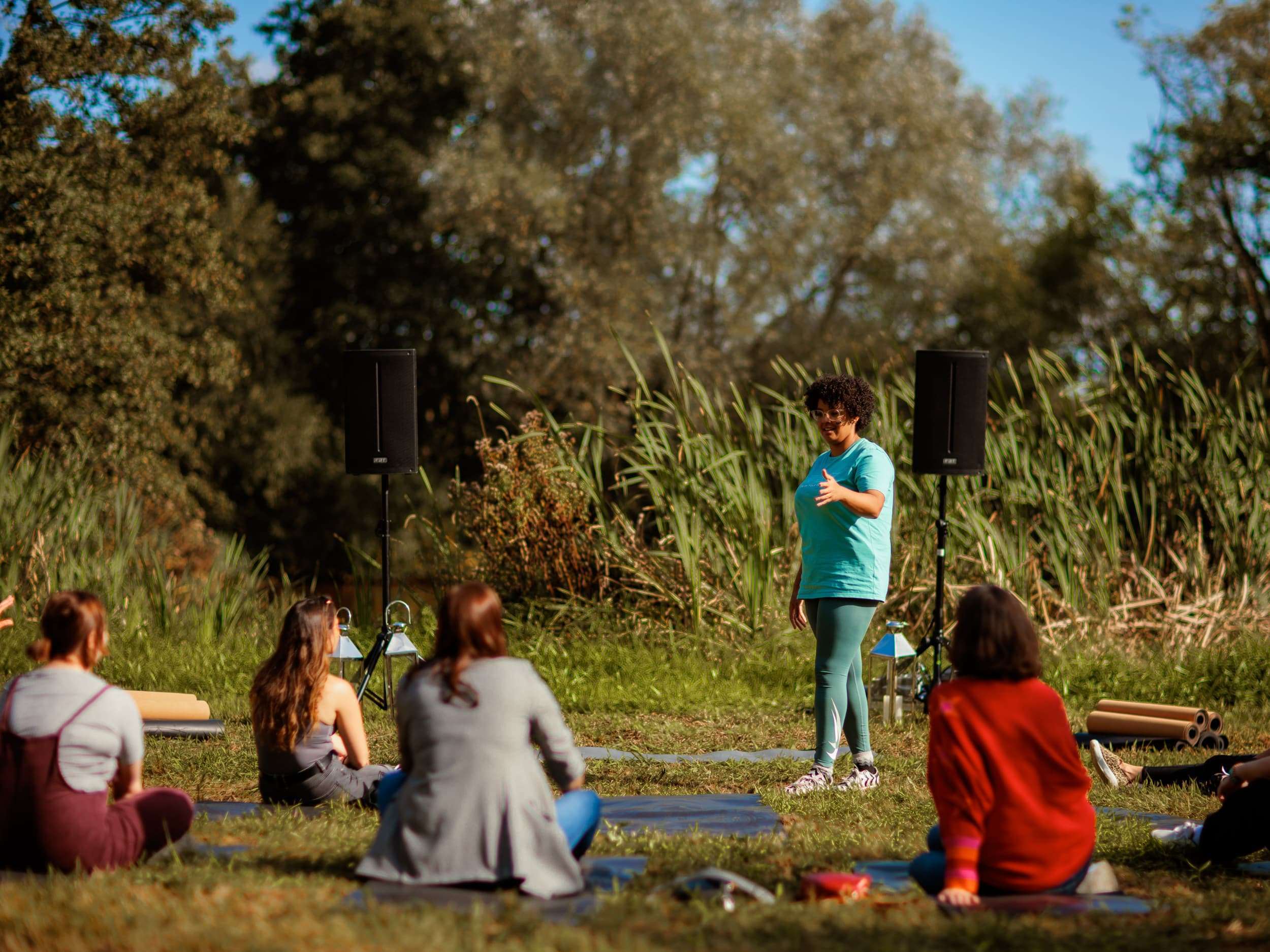 Harriette – Your Friendly Breathing Coach – outdoor workshop Harriette leading a workshop outside – she is smiling as her students site cross-legged on the floor.