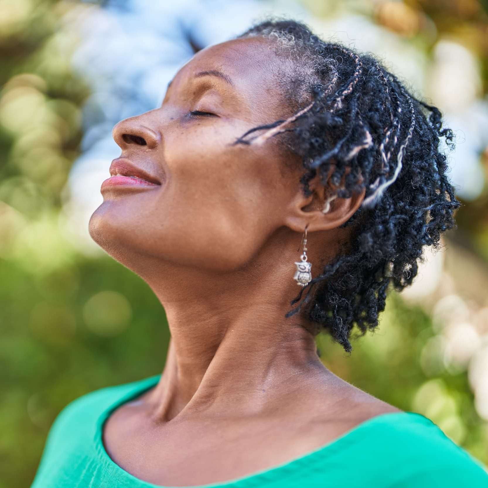Woman out in nature smiling A relaxed older black woman outside taking a breather.